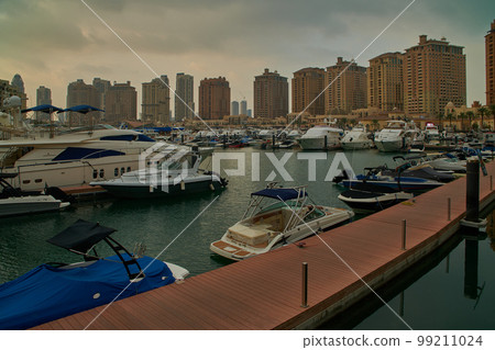 Porto Arabia Marina in The pearl , Doha, Qatar  sunset  shot showing luxurious yachts and boats docked at the marina with  residential buildings in background.  99211024