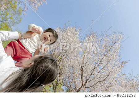 A mother holding her daughter in a cherry blossom park A mother holding her daughter in a cherry blossom park 99211258