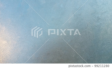 Abstract frosty pattern on glass, background texture. Frozen windshield. Granular structure of transparent ice. The sky is shining through. Abstract ice background. 99211280
