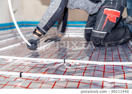 manual installation of underfloor heating in a new building. professional worker manual installation of underfloor heating in a new building. professional worker 99211448