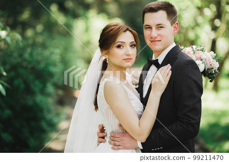 Beautiful romantic wedding couple of newlyweds hugging in park 99211470