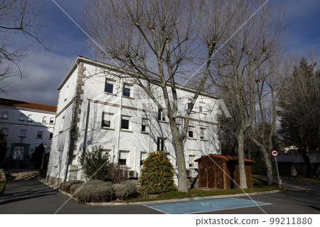 Building. White colored building next to some bare and leafless trees in the surroundings. Building corner. Building. White colored building next to some bare and leafless trees in the surroundings. Building corner. 99211880