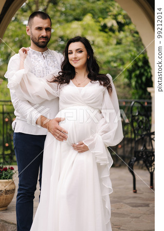 Elegant pregnant woman in luxury white dress walking aroung with her handsome husband 99212014