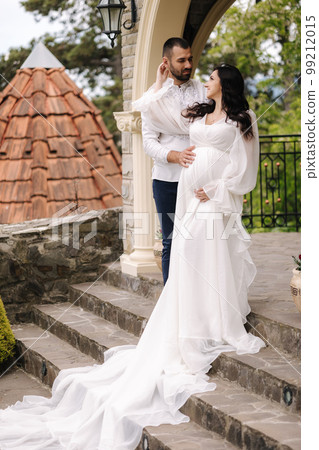 Elegant pregnant woman in luxury white dress walking aroung with her handsome husband Elegant pregnant woman in luxury white dress walking aroung with her handsome husband 99212015