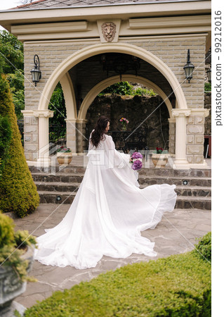 Back view of elegant pregnant woman in beautiful white dress walking outdoors Back view of elegant pregnant woman in beautiful white dress walking outdoors 99212016