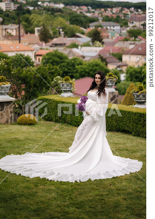Elegant pregnant woman in beautiful white dress walking outdoors Elegant pregnant woman in beautiful white dress walking outdoors 99212017