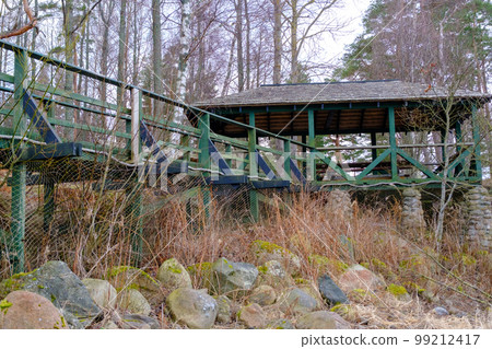 Wooden canopy, sitting area in green. Wooden walkway with railings Wooden canopy, sitting area in green. Wooden walkway with railings 99212417