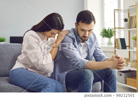 Young woman trying to make peace with husband after quarrel sitting on sofa at home. Young woman trying to make peace with husband after quarrel sitting on sofa at home. 99212501