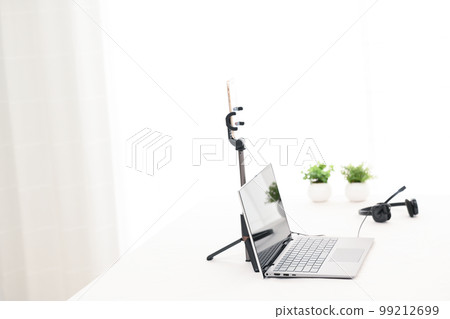 A white table with a laptop, smartphone and headphones for live streaming A white table with a laptop, smartphone and headphones for live streaming 99212699
