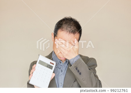 A middle-aged man who has a calculator and is struggling with household finances A middle-aged man who has a calculator and is struggling with household finances 99212761