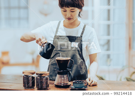 A young female clerk making drip coffee in a coffee kettle 99214418