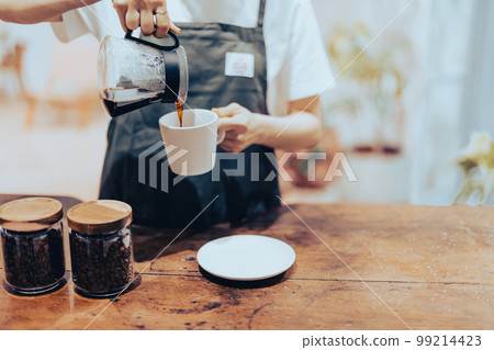 Hand of a part-time worker who puts coffee in a cup 99214423