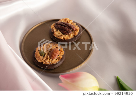 Chocolate florentine on a golden tray Pink background and tulips 99214930