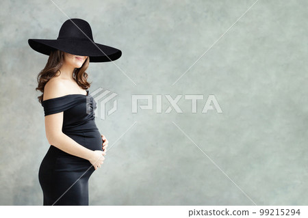 Fashion portrait of pregnant woman in black dress and in wide black broad brim hat  99215294