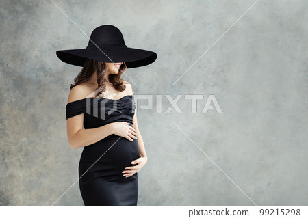 Cheerful pregnant woman in wide black broad brim hat portrait. 99215298
