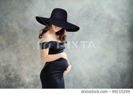 Fashion beauty portrait of beautiful pregnant woman in black dress and black wide hat 99215299