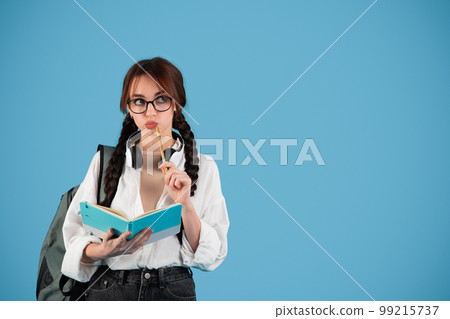 Pensive smart inspired caucasian teen girl with pigtails in glasses with headphones student with backpack 99215737