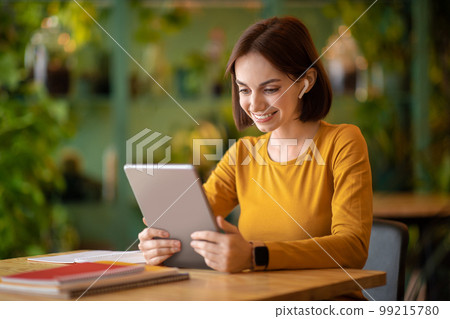 Cheerful brunette lady freelancer working at cafe 99215780
