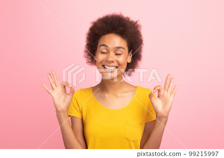 Happy pretty young black curly lady with closed eyes meditates, practices yoga, enjoy calm and comfort 99215997