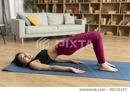 Domestic fitness concept. Young asian lady doing glute bridge exercise for buttocks and legs muscles at home 99216147