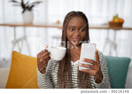 Selective focus on female hands holding coffee mug and phone 99216149