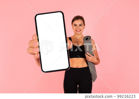 Online Offer. Sporty Young Lady With Yoga Mat Showing Big Blank Smartphone 99216223