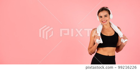 Portrait Of Beautiful Sporty Female Wearing Wireless Headphones And Towel Around Neck 99216226