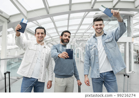 Three Male Friends Traveling Showing Boarding Pass Tickets In Airport 99216274