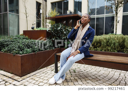 Beautiful young african woman using mobile phone in the street 99217461