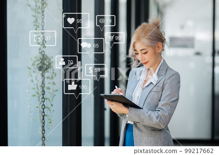 Asian woman typing smartphone, keyboard  with laptop computer of Social media and Marketing virtual icons screen concept. 99217662