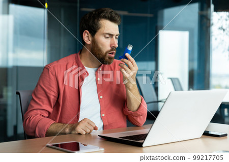 Asthma and respiratory problems in office worker, mature man coughing and using medicine in inhaler to ease breathing at workplace, mature businessman inside office with laptop. Asthma and respiratory problems in office worker, mature man coughing and using medicine in inhaler to ease breathing at workplace, mature businessman inside office with laptop. 99217705