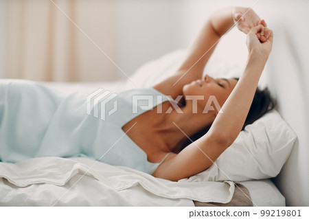 Healthy young woman dressing nightie lying on bed in bedroom. 99219801