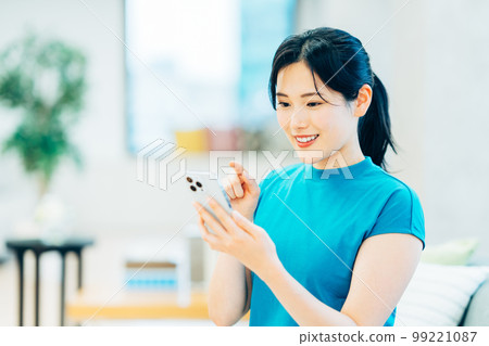 在客廳裡操作智能手機的年輕女子 99221087