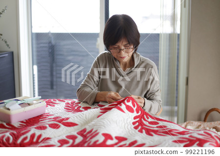 A woman making a Hawaiian quilt 99221196