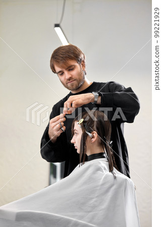 Professional male hairdresser cutting female hair in salon 99221929