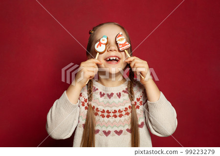 Funny joyful child girl having fun with Santa Claus and Snowman gingerbreads  99223279