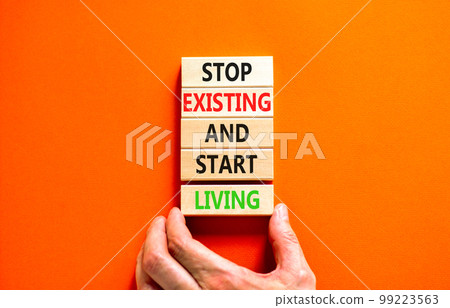 Stop existing start living symbol. Concept words Stop existing and start living on wooden blocks. Beautiful orange table orange background. Business Stop existing start living concept. Copy space. 99223563