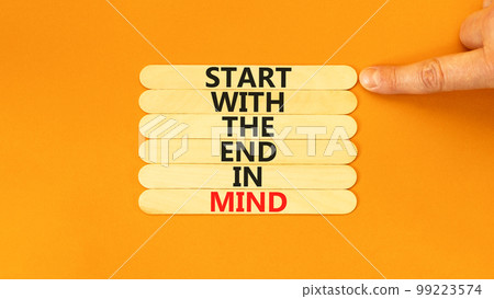 Start in end of mind symbol. Concept words Start with the end in mind on wooden stick. Beautiful orange table orange background. Businessman hand. Business start in end of mind concept. Copy space. 99223574