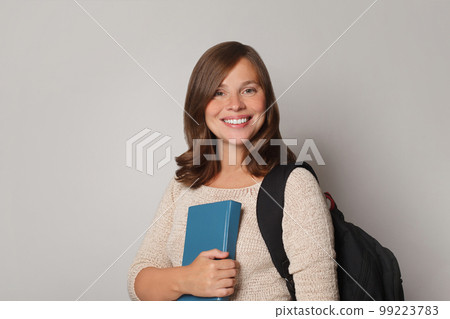 Pretty smiling joyfully brunette female dressed casually, looking with satisfaction at camera Pretty smiling joyfully brunette female dressed casually, looking with satisfaction at camera 99223783