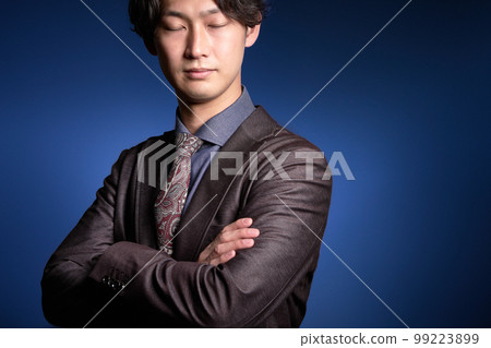 Young business person closing his eyes while folding his arms Young business person closing his eyes while folding his arms 99223899