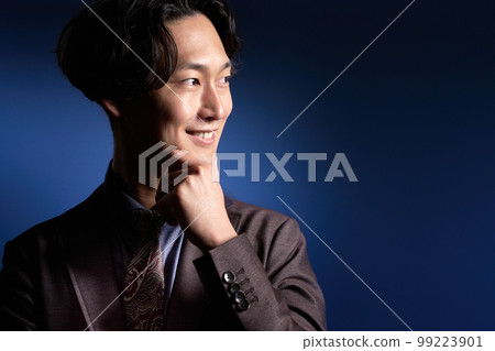 一個微笑並將目光轉向一邊的年輕商人 99223901