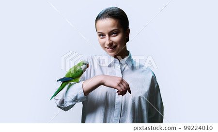 Young teenage female with green pet parrot, on white background 99224010