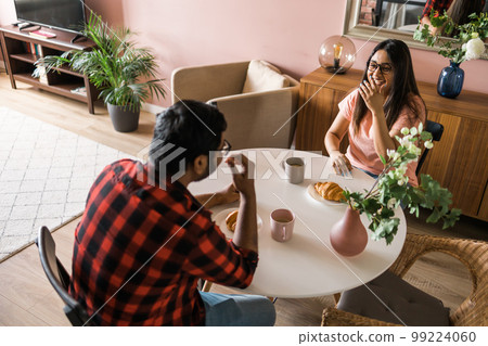 Happy indian couple having breakfast and small talk together in the kitchen - friendship, dating and family Happy indian couple having breakfast and small talk together in the kitchen - friendship, dating and family 99224060