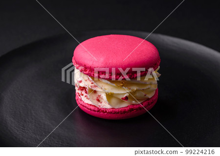 Beautiful tasty macaron with filling and fruit flavor on a black plate Beautiful tasty macaron with filling and fruit flavor on a black plate 99224216