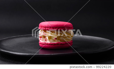 Beautiful tasty macaron with filling and fruit flavor on a black plate 99224220