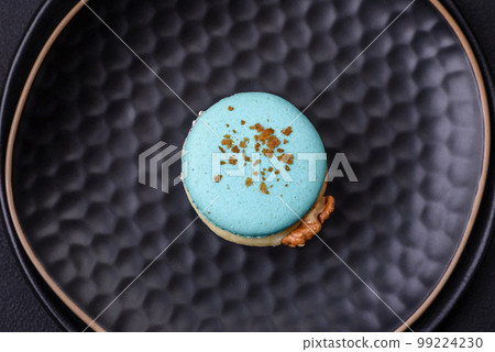 Beautiful tasty macaron with filling and fruit flavor on a black plate Beautiful tasty macaron with filling and fruit flavor on a black plate 99224230