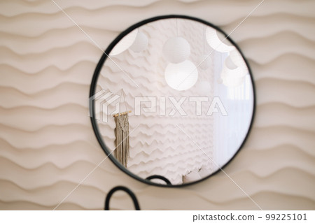 Modern interior with stylish round mirror by beige wall in a cozy room, copy space, elegant accessories in stylish home decor Modern interior with stylish round mirror by beige wall in a cozy room, copy space, elegant accessories in stylish home decor 99225101