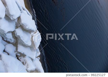 Huge broken ice floes lie on the river bank. Texture. 99225127