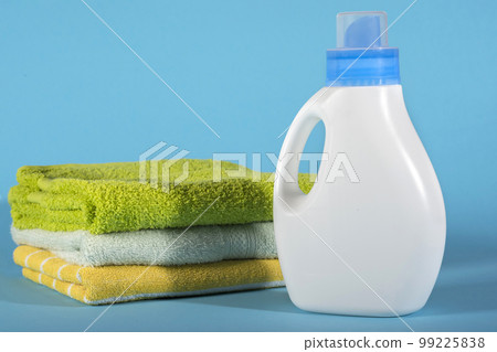 Bottle with detergent and towels on a blue background Bottle with detergent and towels on a blue background 99225838