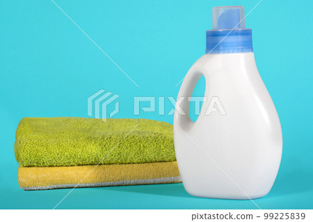 White plastic bottle of detergent and clean towels on a blue background White plastic bottle of detergent and clean towels on a blue background 99225839